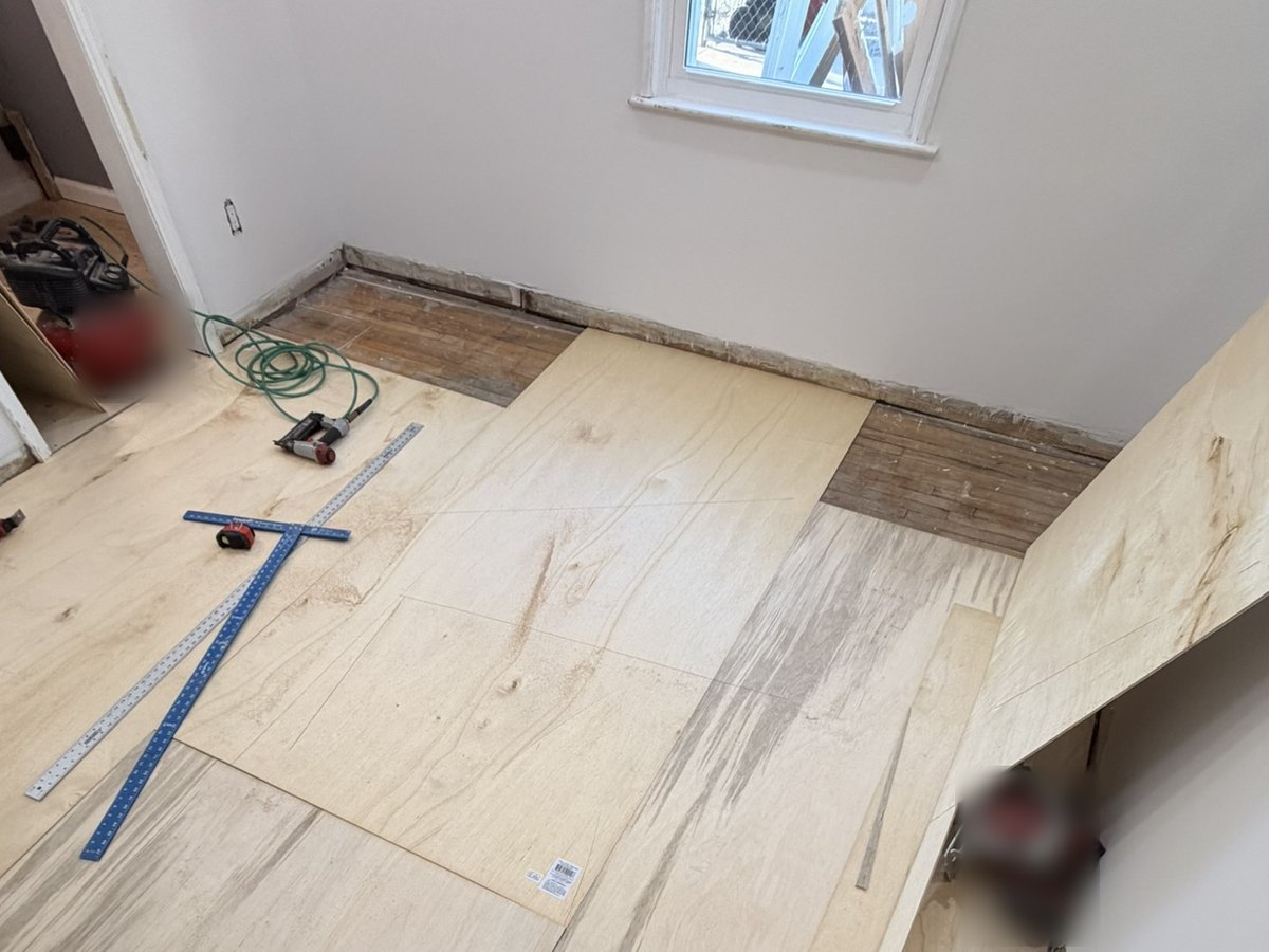 Whole room of new plywood underlayment with staggered seams, squares and tools laid out